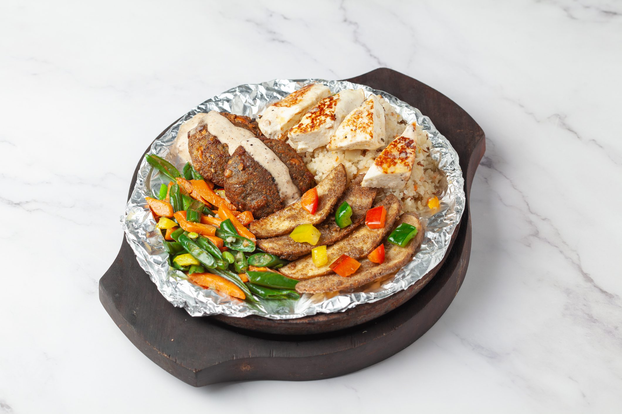Close-up of veg vrat or fasting or upvas  sizzlers with paneer, potatoes carrots wooden plate, served burning  hot with fumes at table